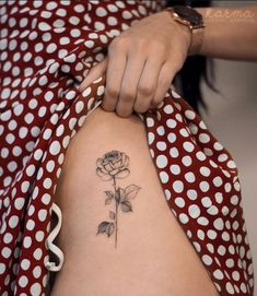 a woman with a rose tattoo on her arm and leg, holding onto a polka dot dress