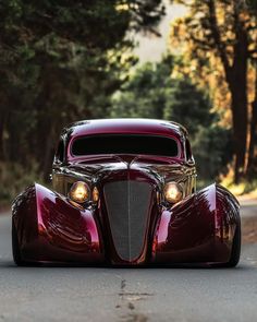 an antique car is parked on the side of the road in front of some trees