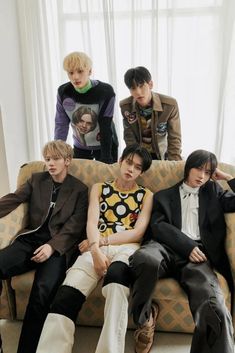 four young men sitting on a couch in front of a window