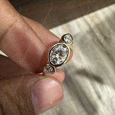 a person is holding a ring with two stones in it's middle and the other side