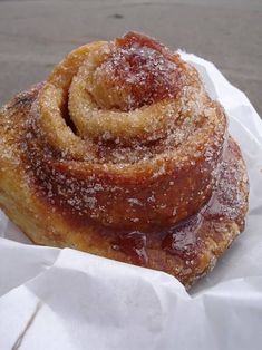 a cinnamon roll sitting on top of a piece of wax paper covered in powdered sugar