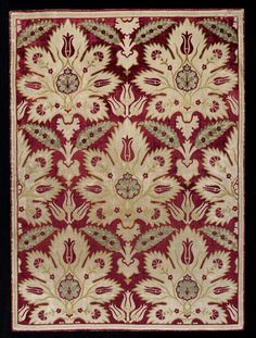 a red and beige rug with an ornate design on it's side, in black frame