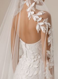 the back of a bride's wedding dress with white flowers and leaves on it