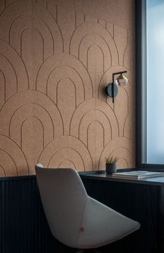 a white chair sitting in front of a window next to a wall mounted light on the side of a wooden table