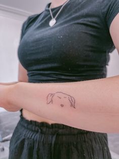 a woman with a small dog tattoo on her left arm and right arm behind her back