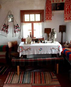 a table with a white cloth on it in front of a window and rugs