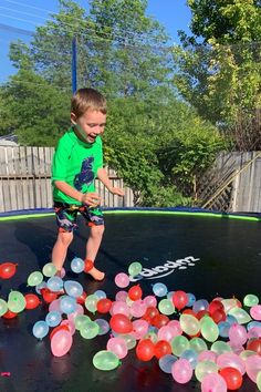 a young boy standing on top of a trampoline filled with balloons