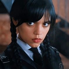 a woman with black hair wearing a uniform and braids on her head, looking at the camera