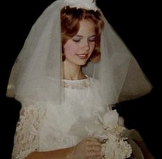 an old photo of a woman in her wedding dress and veil holding a bridal bouquet