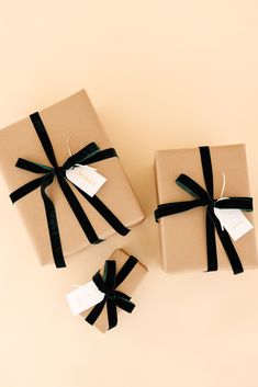 three wrapped presents with black ribbons and tags