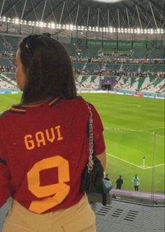 a woman standing in front of a large stadium filled with people and looking at the field