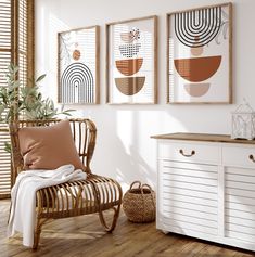 a white room with three framed art pieces on the wall and a wicker chair next to it