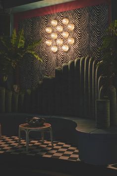 a black and white checkered floor in front of a wall with lights on it