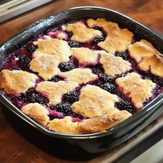 a blueberry cobbler in a black dish on a wooden table