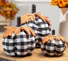 three black and white pumpkins sitting on top of a wooden table