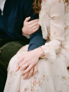 a man and woman sitting next to each other with their hands wrapped around the couple's fingers