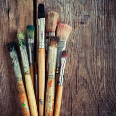 paintbrushes lined up in a row on a wooden surface