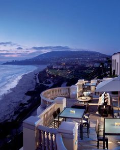 an outdoor dining area overlooking the ocean at dusk