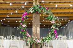 a wooden pole decorated with pink flowers and greenery for a wedding reception at the barn