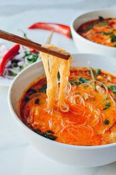 two bowls of soup with chopsticks sticking out of one bowl and another bowl in the other