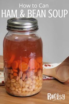 a jar filled with beans and carrots next to a wooden spoon on a table