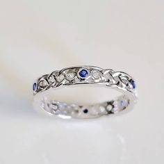 a white gold ring with blue sapphires and diamonds in the center, on a white background