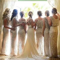 a group of women standing next to each other in front of a window wearing gold dresses