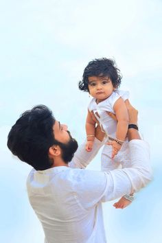 a man holding a baby up to his face while he holds it in the air