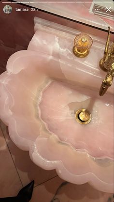 a pink sink with gold faucets on it