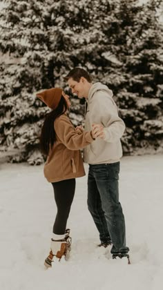 a man and woman are standing in the snow