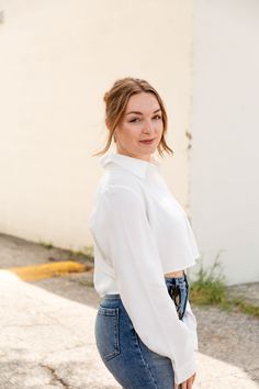 This button up blouse is short and sweet. Our Tell Me More Cropped blutton up blouse is simple, but effective, a twist on the basic white button up, but still timeless enough for everyday wear. The cropped length adds a playful touch to your wardrobe, perfect for pairing with high-waisted anything! Emphasize that classic look with a simple pair of denim jeans, or spice things up with a statement trouser and pair of heels. cropped button up front chest pocket long sleeves collar cropped, relaxed Tell Me More, Mama Necklace, Romper And Jacket, Short And Sweet, White Button Up, Button Up Blouse, Circle Necklace, Chest Pocket, Classic Looks