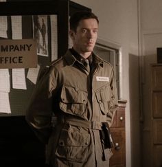 a man in an army uniform standing next to a sign that says company office on it