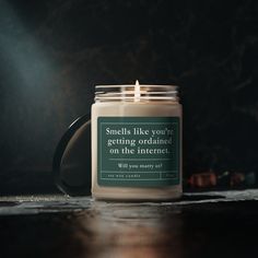 a candle sitting on top of a wooden table next to a black mug with a quote