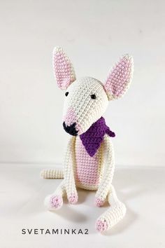 a crocheted rat with a purple bow tie sitting on top of it's legs