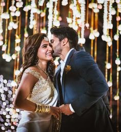 a man and woman kissing in front of lights