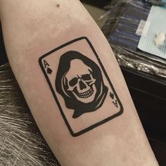 a skull in a card tattoo on the arm