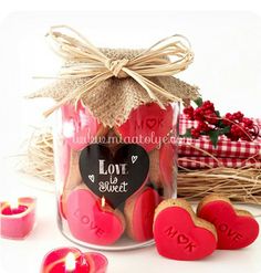 two heart shaped cookies in a jar next to some candles and other valentine's day decorations