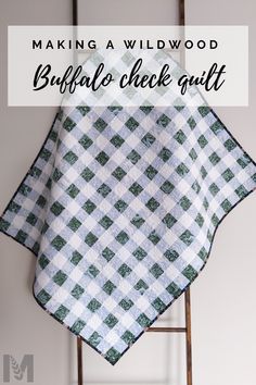 a white and green checkered blanket hanging on a ladder with the words making a wildwood buffalo check quilt