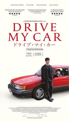 a man standing next to a red car in front of a movie poster for drive my car