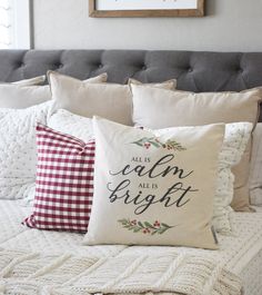 a bed with pillows that say all the calm is bright on it and holly wreaths