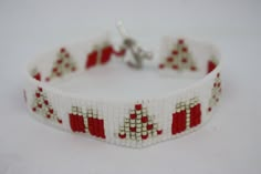 a red and white beaded bracelet with christmas trees on the front, in rows of squares