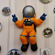 an orange astronaut doll laying on top of a table next to plates and spoons