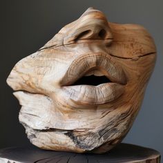 a wooden sculpture that looks like a human face with its mouth open and tongue out