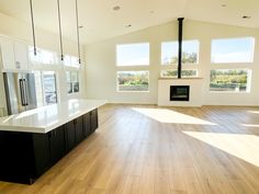 an empty living room with wood floors and white cabinets in the center, windows on both sides