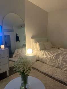 a room with a bed, mirror and table in it that has flowers on it