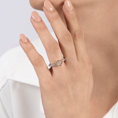 a woman's hand with a diamond ring on her left hand and a white shirt on the right