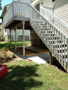 a white staircase leading up to a deck in a back yard with grass and trees