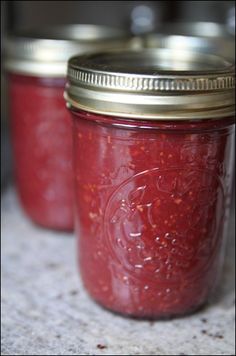 three jars filled with red liquid sitting on top of a counter