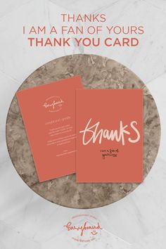 an orange thank card with the words thanks on it in white and red ink, sitting on top of a marble table