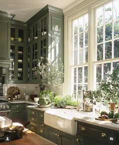 a kitchen filled with lots of green cupboards and counter top next to a window